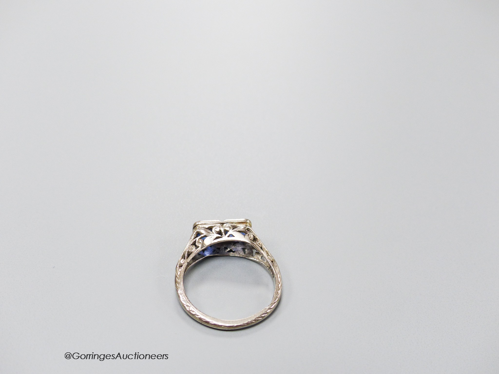 A 1920's white metal (stamped 18ct & plat) and two stone sapphire set ring with carved and single stone diamond chip set shoulders, size K, gross weight 3.2 grams